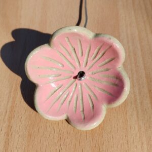 fleur en céramique montée sur tige. Fond couleur rose, avec nervures gravées