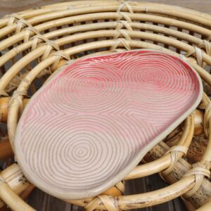 Plat "sillon" rose et rouge, en céramique artisanale, gravé de lignes concentriques selon la technique du sgraffito