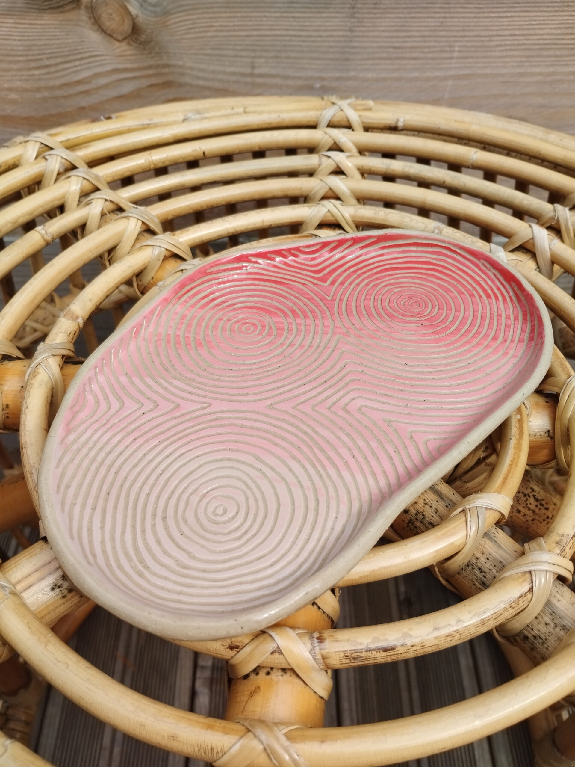 Plat "sillon" rose et rouge, en céramique artisanale, gravé de lignes concentriques selon la technique du sgraffito