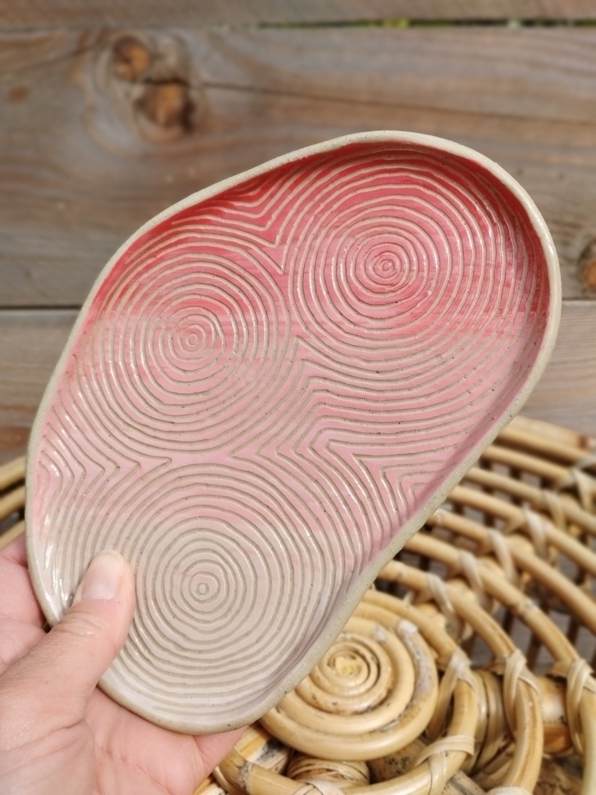 Plat "sillon" rose et rouge, en céramique artisanale, gravé de lignes concentriques selon la technique du sgraffito