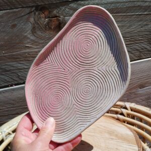 Plat décoratif en céramique. Poterie colorée en dégradé de rose, motif de lignes gravées de cercles concentriques