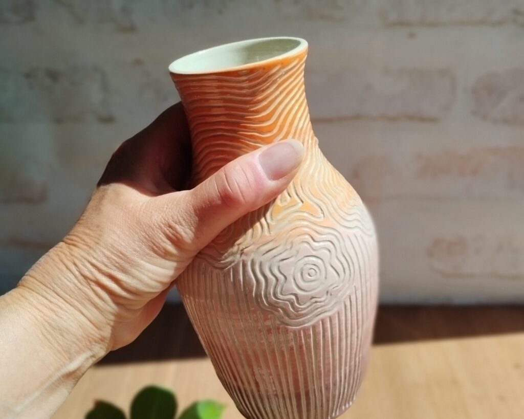 Vase céramique orange et rose avec motif de lignes gravées évoquant des fleurs et des tiges