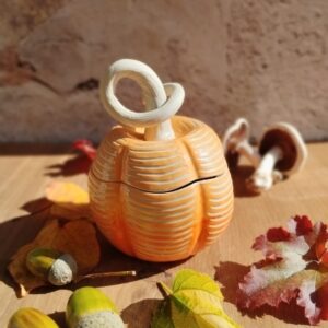Boite en céramique artisanale en forme de citrouille. Fond en dégradé de orange. motif de lignes horizontales gravées