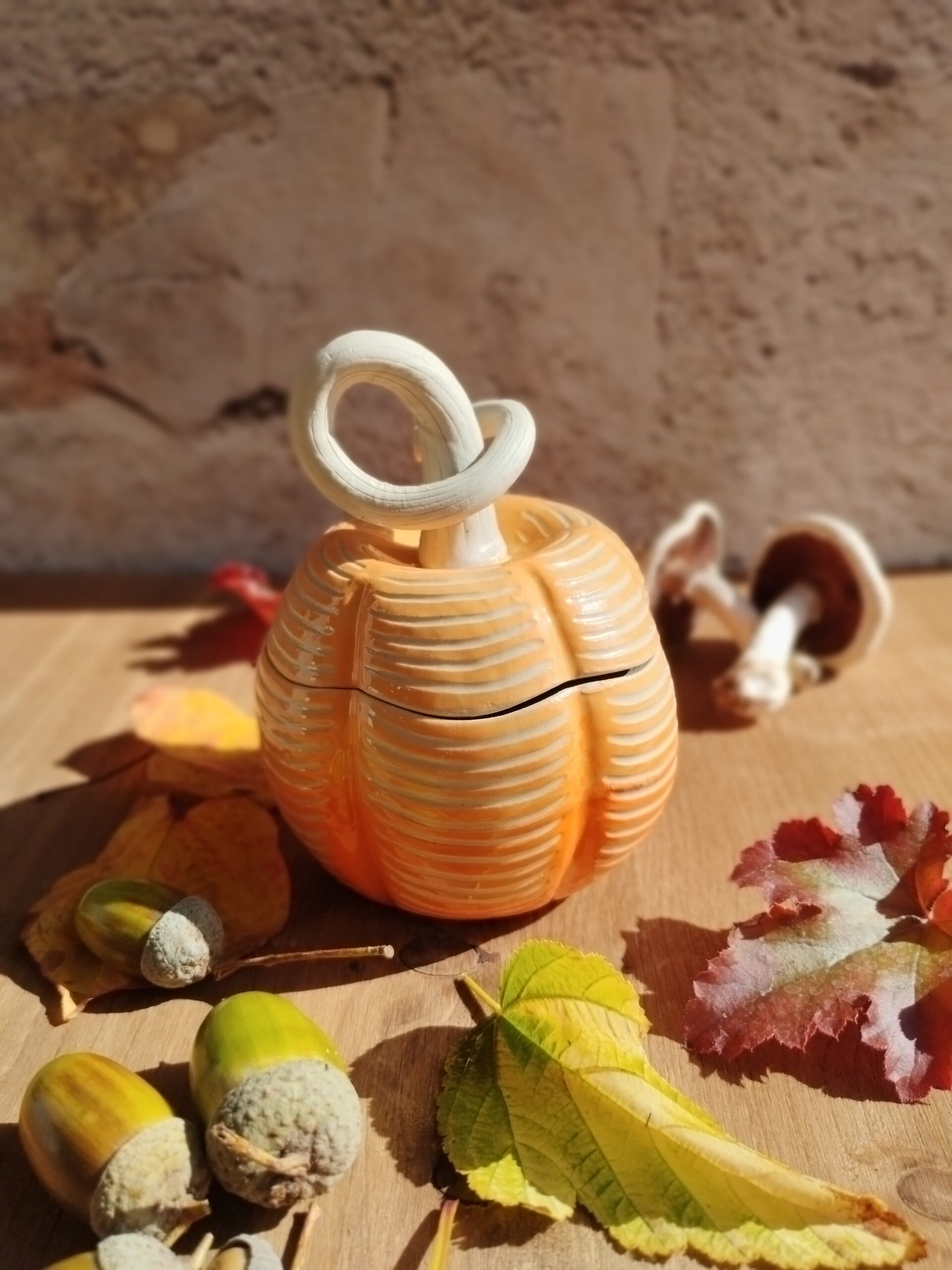 Boite en céramique artisanale en forme de citrouille. Fond en dégradé de orange. motif de lignes horizontales gravées