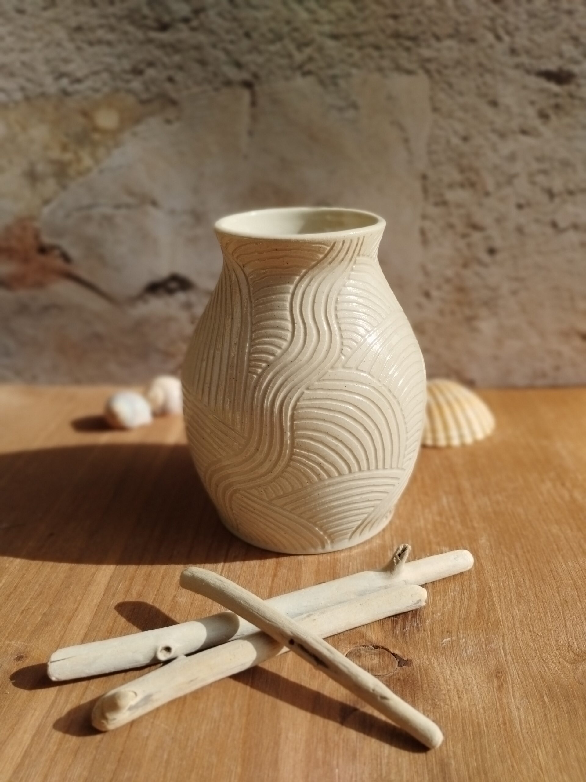 Vase en céramique artisanale écru. Motif de lignes gravées rappelant les mouvements de l'eau