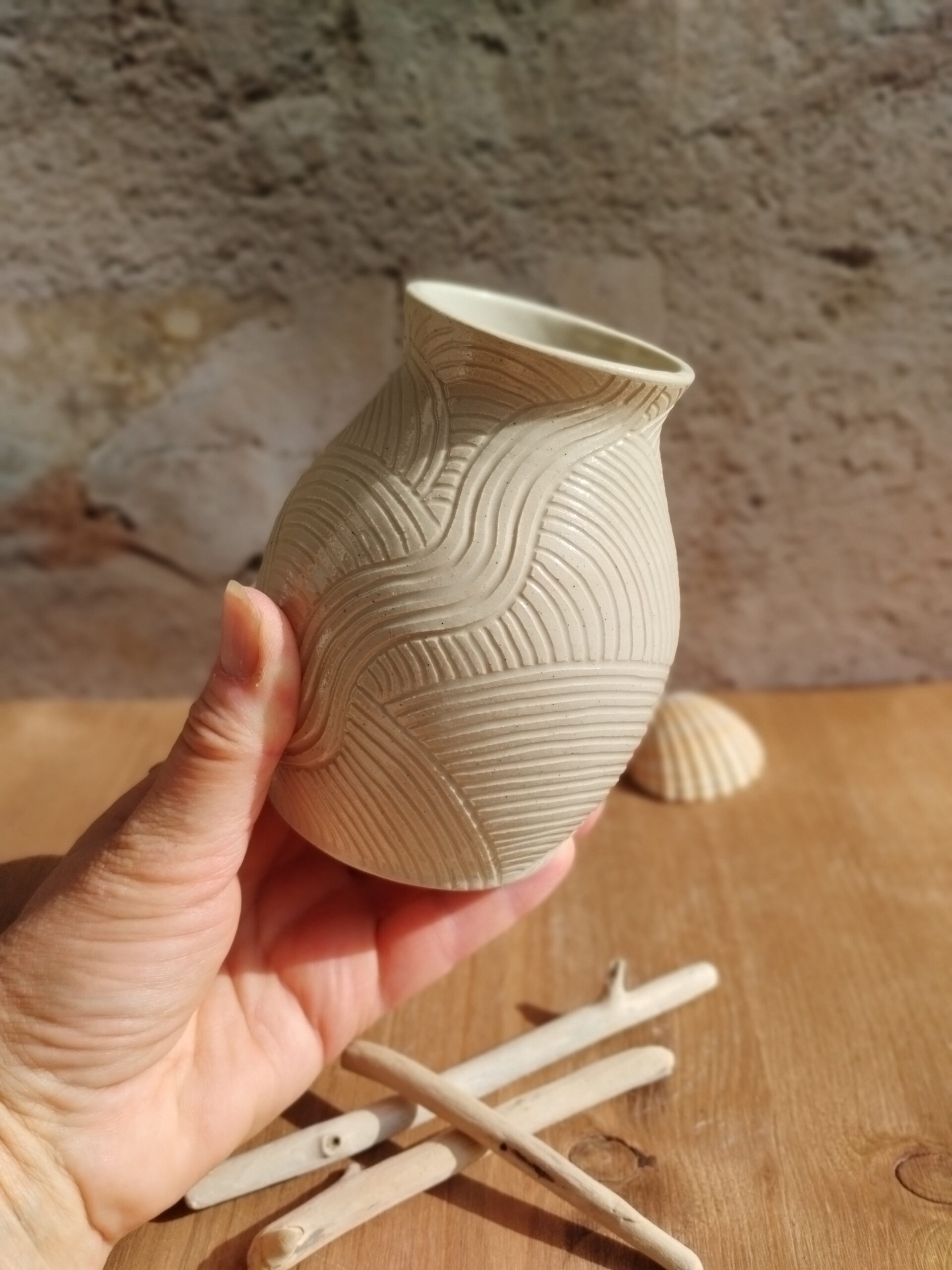 Vase en céramique artisanale écru. Motif de lignes gravées rappelant les mouvements de l'eau