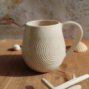 Mug en céramique artisanale écru. Motif de lignes gravées rappelant les mouvements de l'eau.