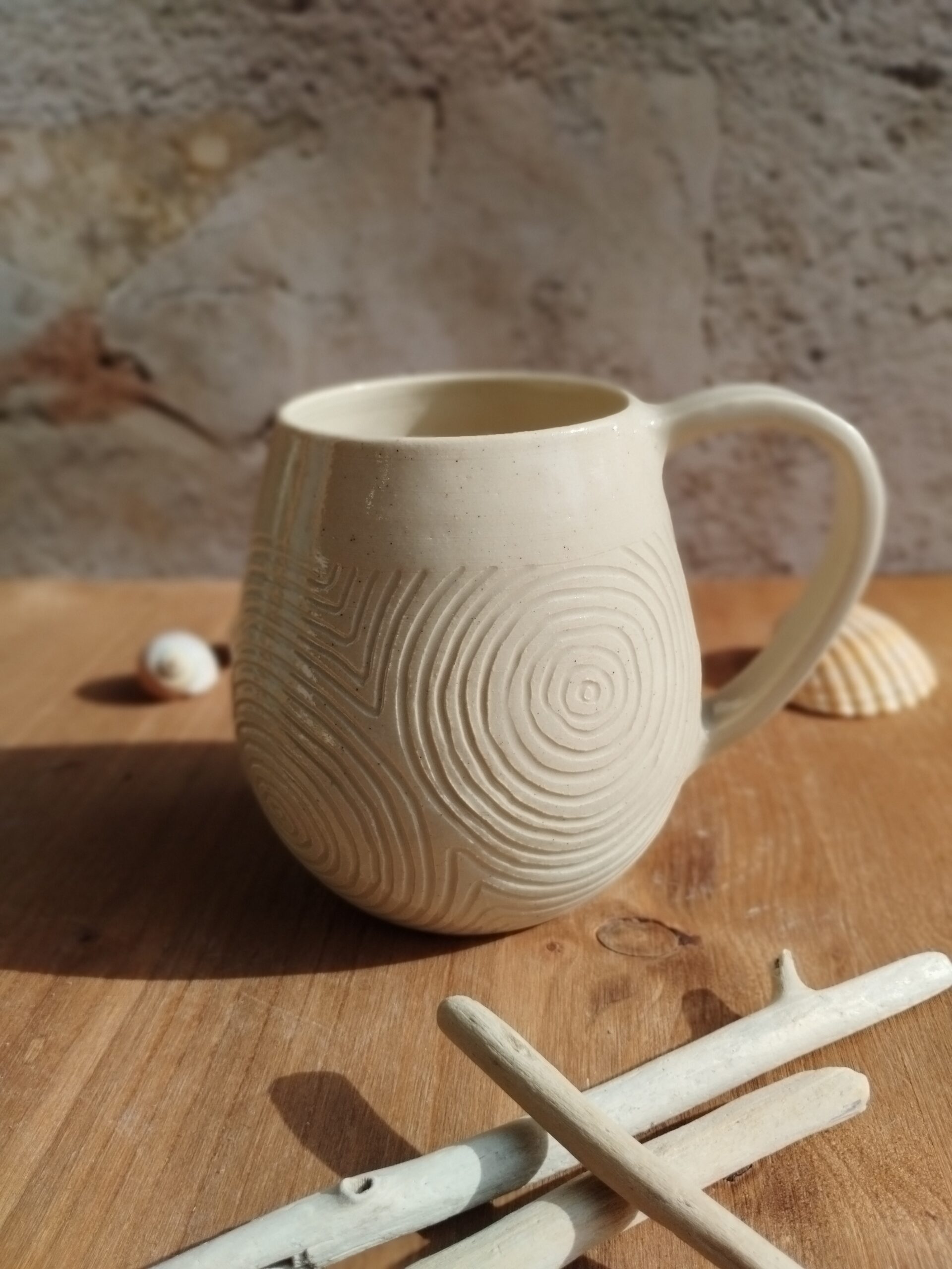 Mug en céramique artisanale écru. Motif de lignes gravées rappelant les mouvements de l'eau.