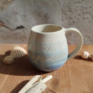 Mug en céramique artisanale. Fond en dégradé de bleu. Motif gravé rappelant les mouvements de l'eau