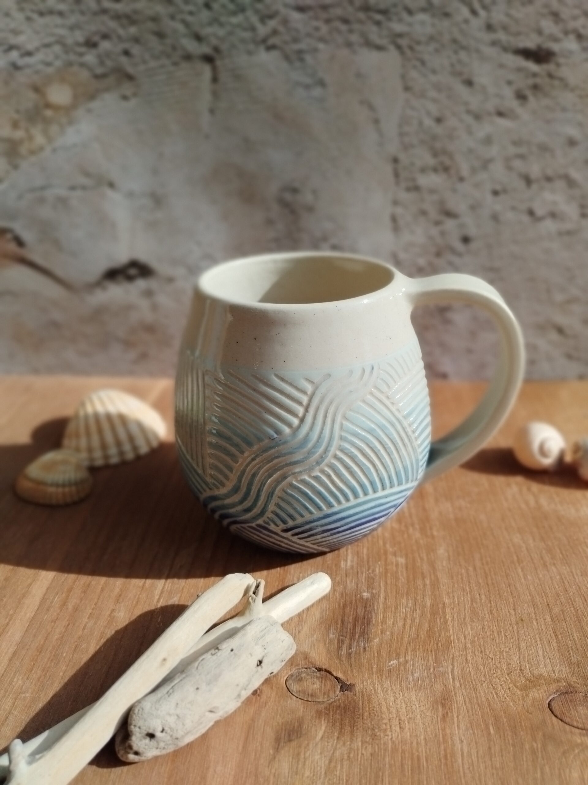 Mug en céramique artisanale. Fond en dégradé de bleu. Motif gravé rappelant les mouvements de l'eau