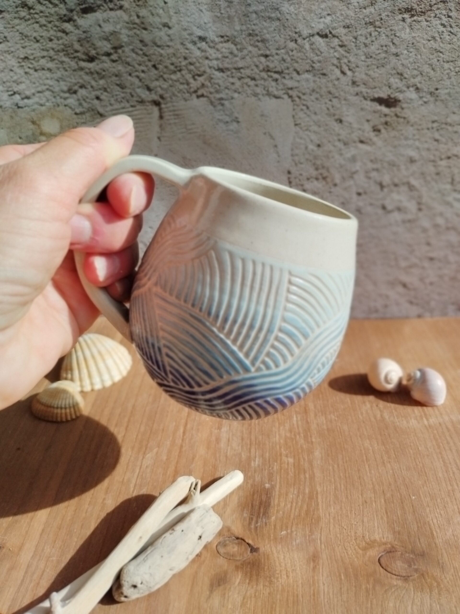 Mug en céramique artisanale. Fond en dégradé de bleu. Motif gravé rappelant les mouvements de l'eau
