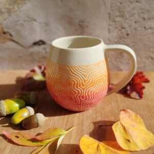mug en céramique artisanale. Fond en dégradé de couleurs rouge orange. Motif gravé feuille de chêne