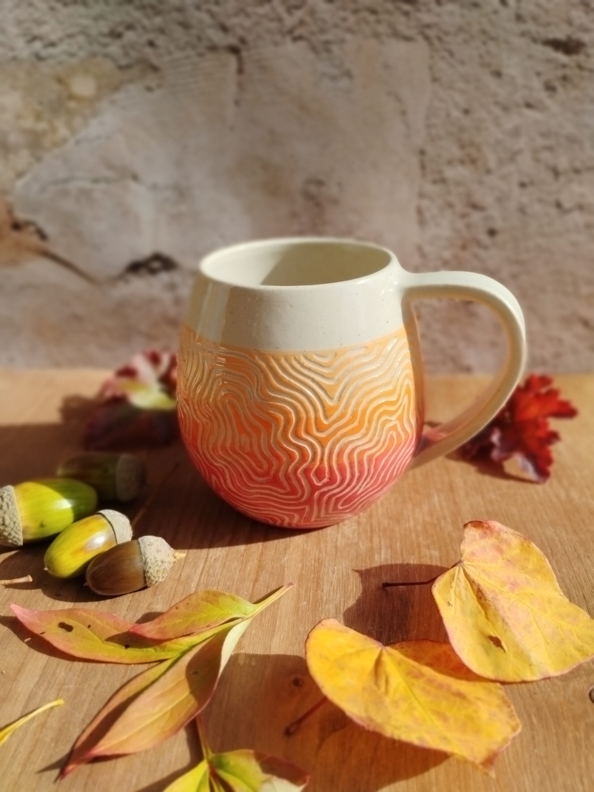 mug en céramique artisanale. Fond en dégradé de couleurs rouge orange. Motif gravé feuille de chêne