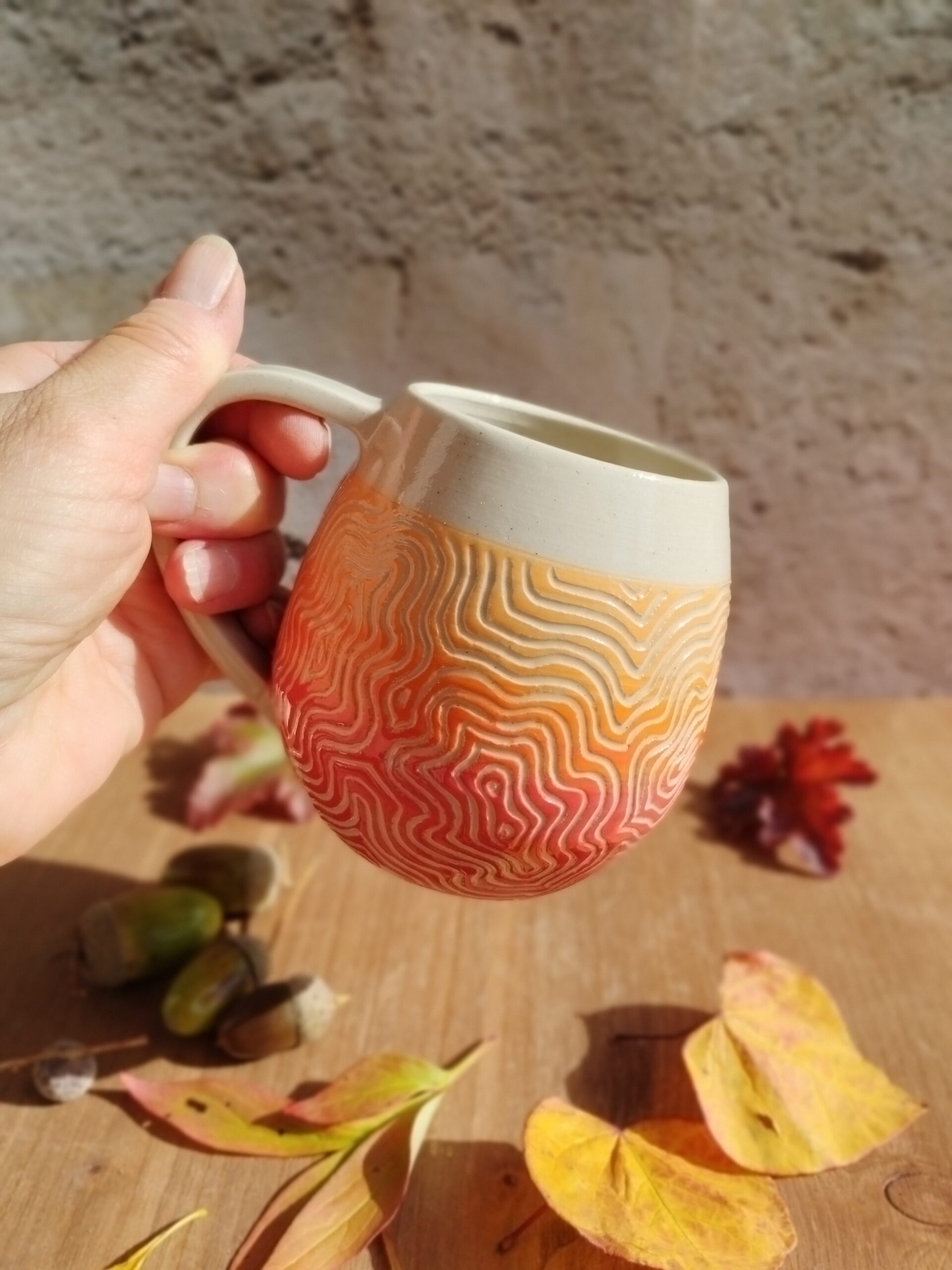mug en céramique artisanale. Fond en dégradé de couleurs rouge orange. Motif gravé feuille de chêne