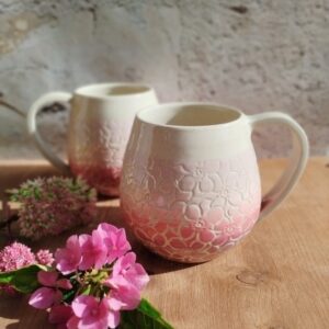 Mug en céramique artisanale. Fond coloré en dégradé de roses, motifs hortensia gravés