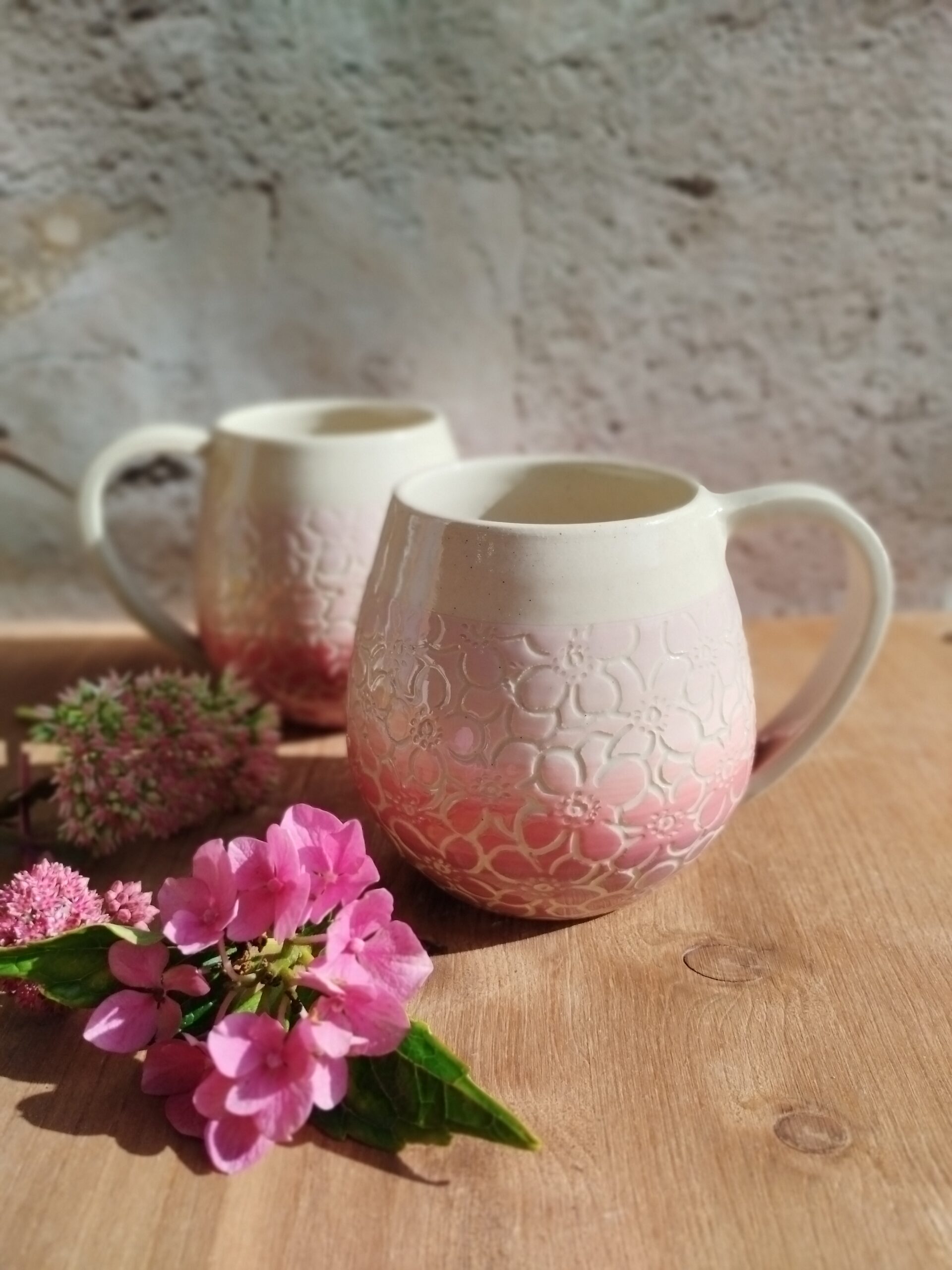 Mug en céramique artisanale. Fond coloré en dégradé de roses, motifs hortensia gravés