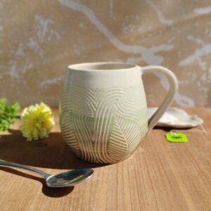 Grand mug en céramique artisanale. Fond en dégradé de vert. Motif de feuillage gravé