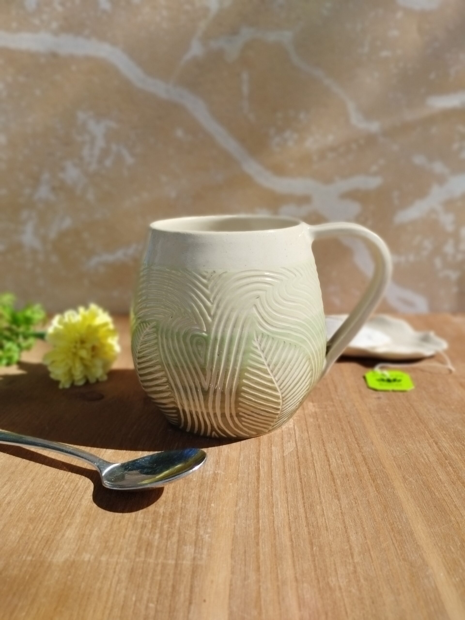 Grand mug en céramique artisanale. Fond en dégradé de vert. Motif de feuillage gravé