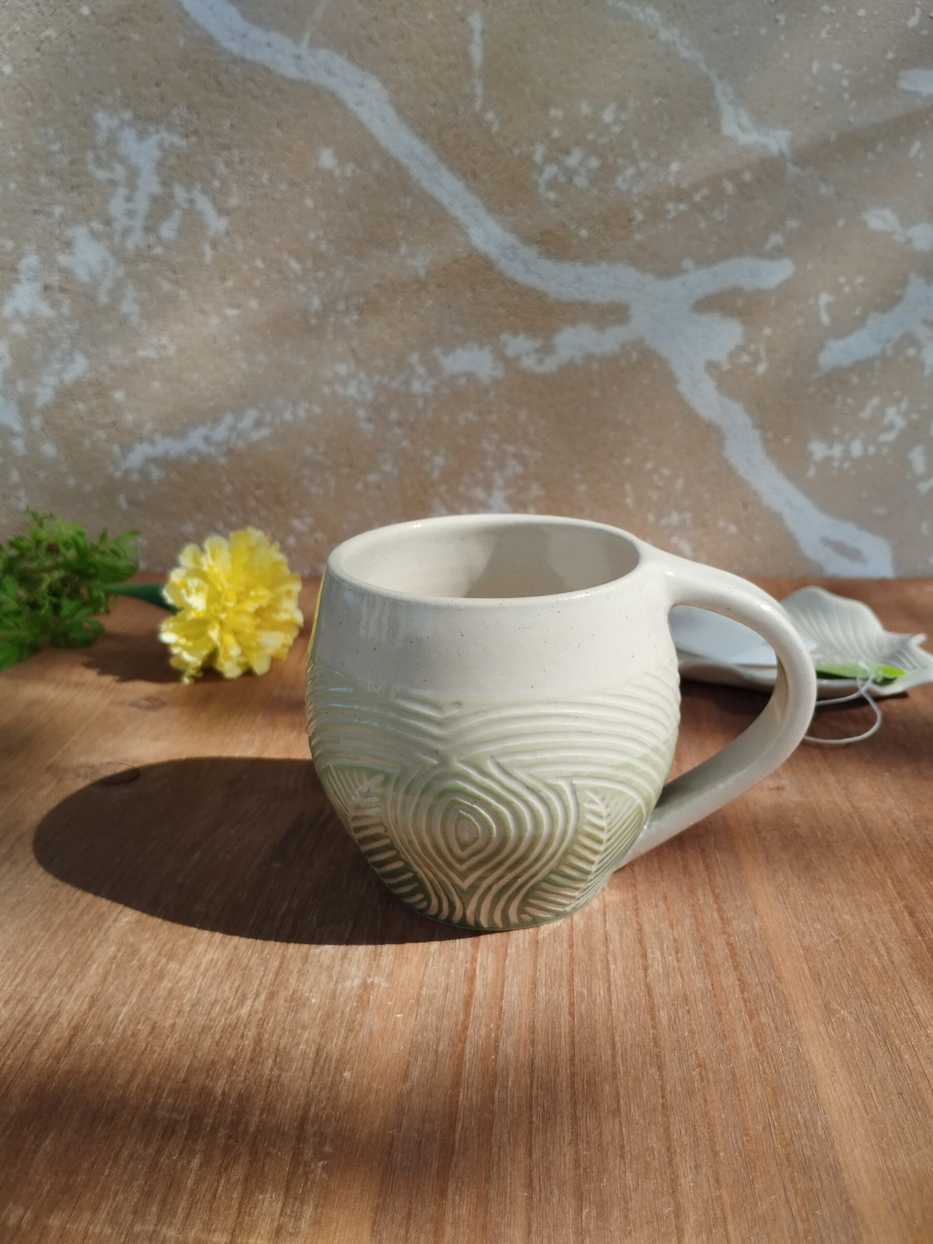 Tasse en céramique artisanale. Fond en dégradé de vert. Motif de lignes gravées feuillage