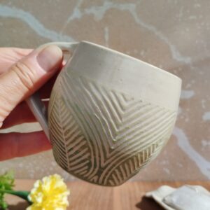 Tasse en céramique artisanale. Fond en dégradé de vert. Motif de lignes gravées feuillage