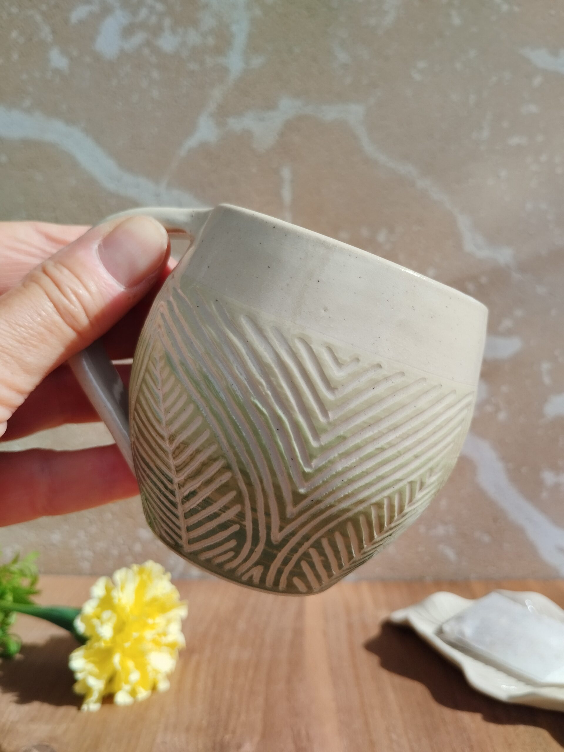 Tasse en céramique artisanale. Fond en dégradé de vert. Motif de lignes gravées feuillage