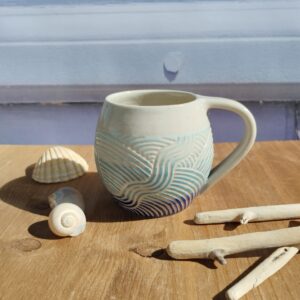 Tasse en céramique artisanale. Fond en dégradé de bleu. motif de lignes gravées aquatique