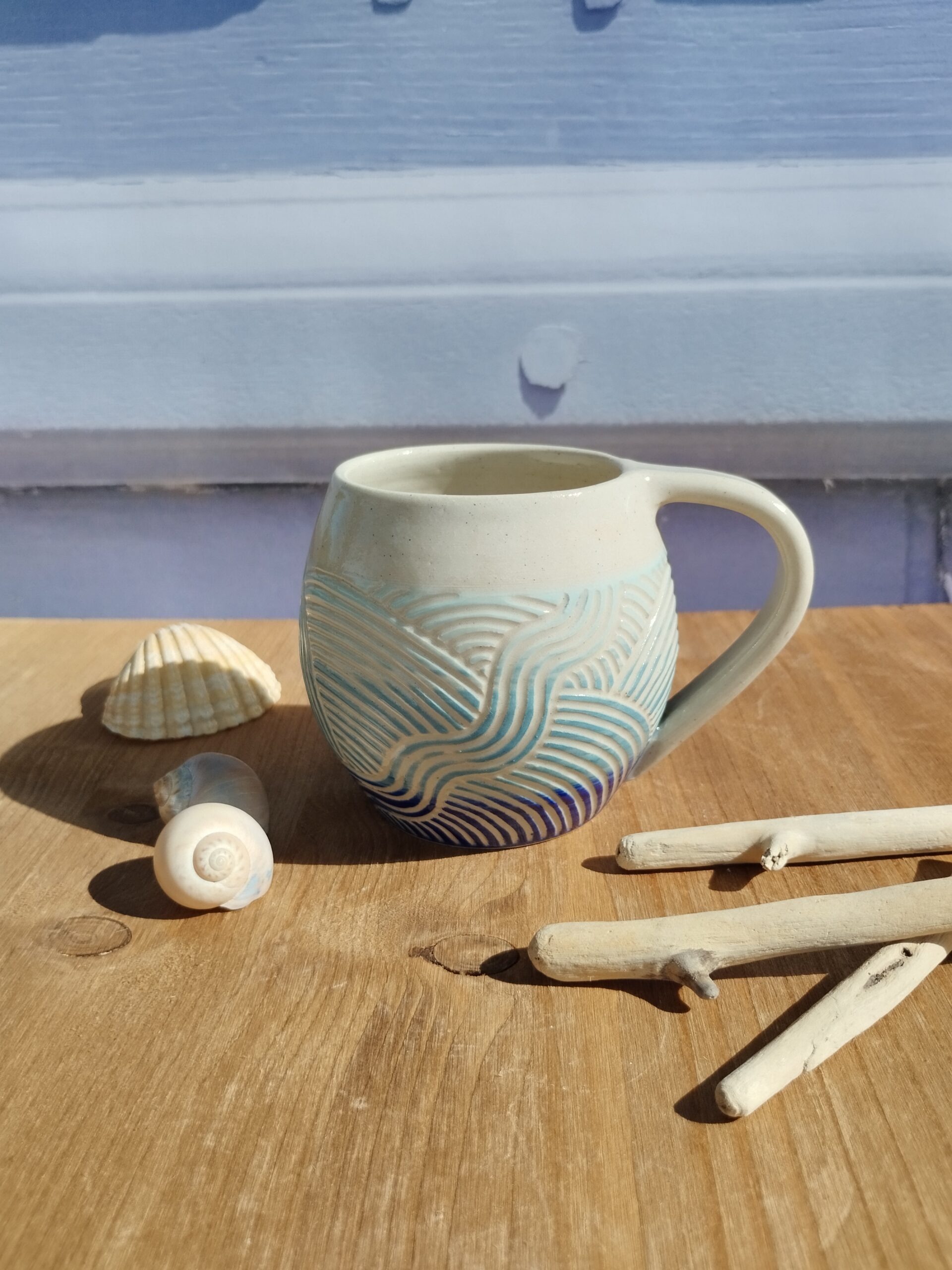 Tasse en céramique artisanale. Fond en dégradé de bleu. motif de lignes gravées aquatique