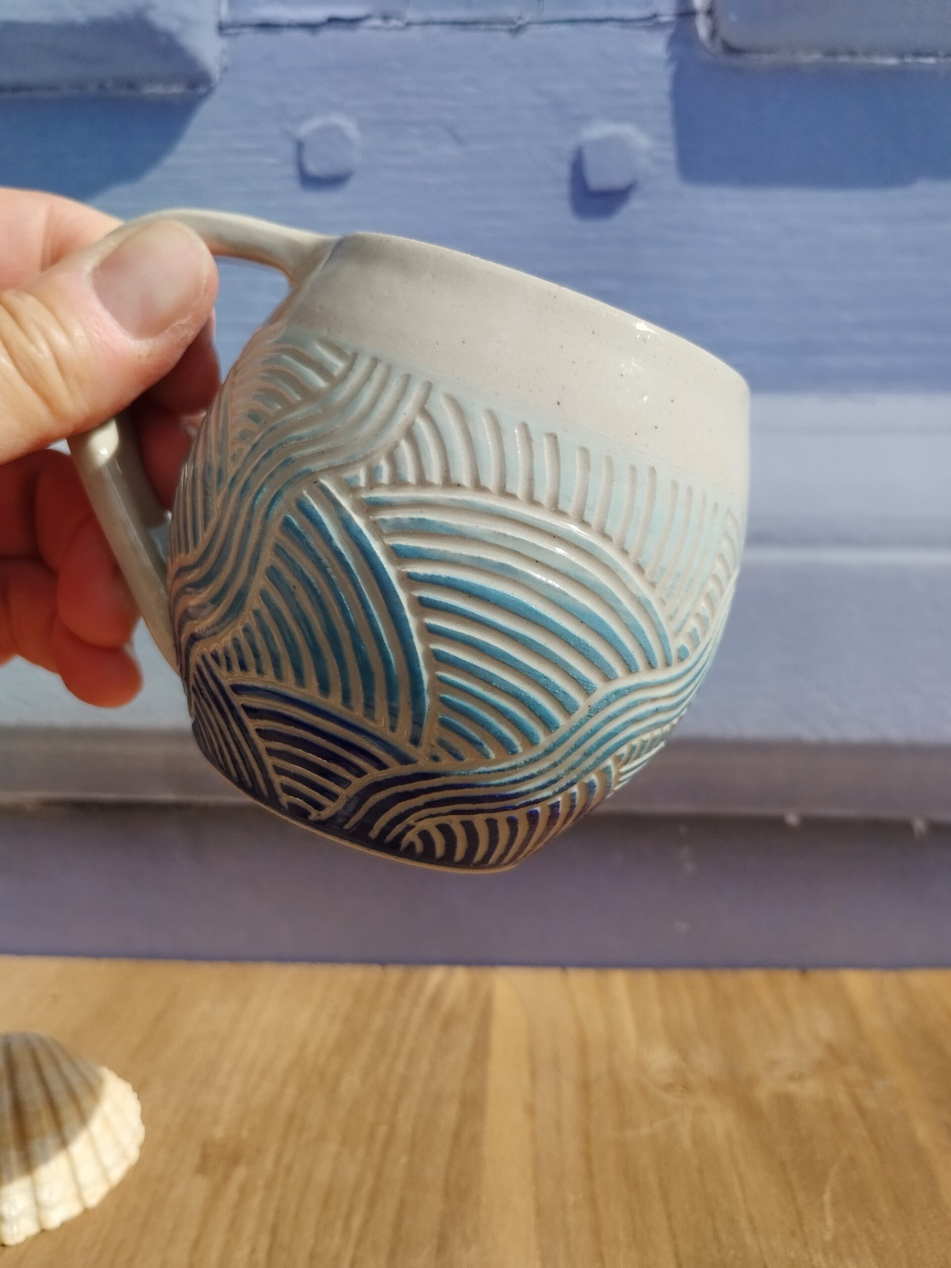 Tasse en céramique artisanale. Fond en dégradé de bleu. motif de lignes gravées aquatique