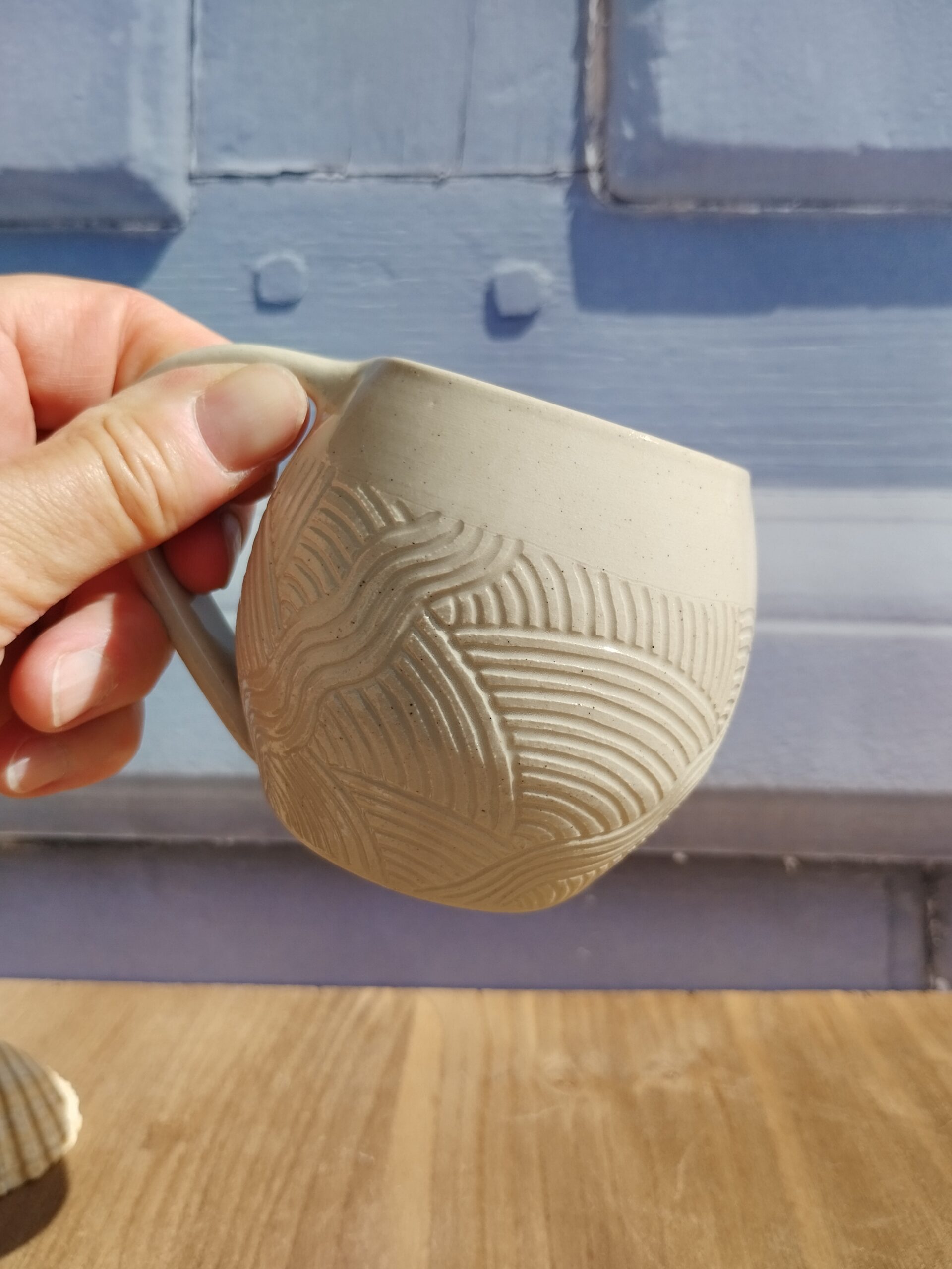 Tasse en céramique artisanale écrue. Motif de lignes gravées aquatique