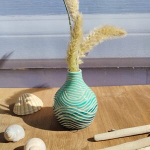mini vase en céramique artisanale. Fond en dégradé de bleus. Motif de lignes gravées en forme de vagues
