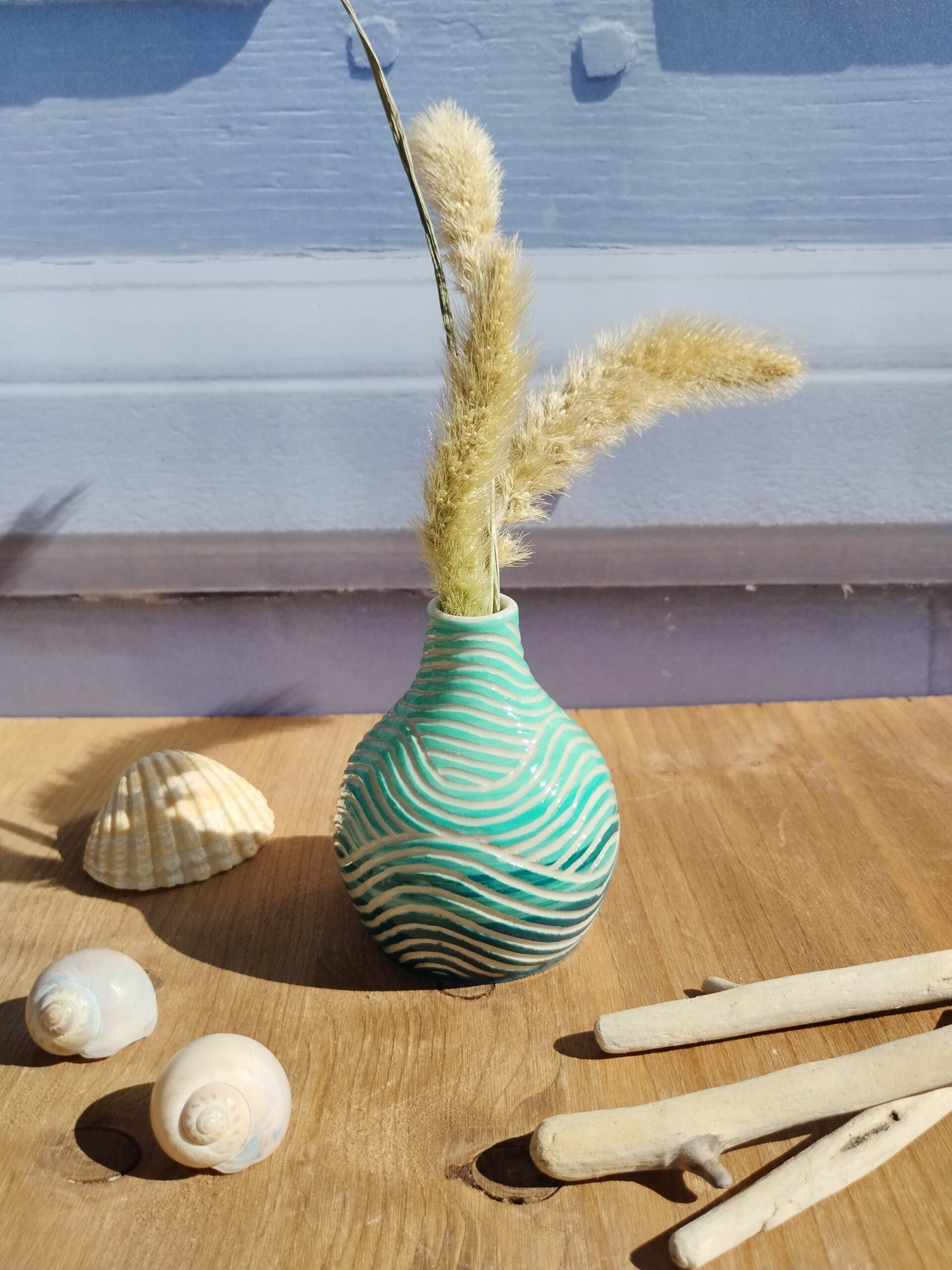 mini vase en céramique artisanale. Fond en dégradé de bleus. Motif de lignes gravées en forme de vagues