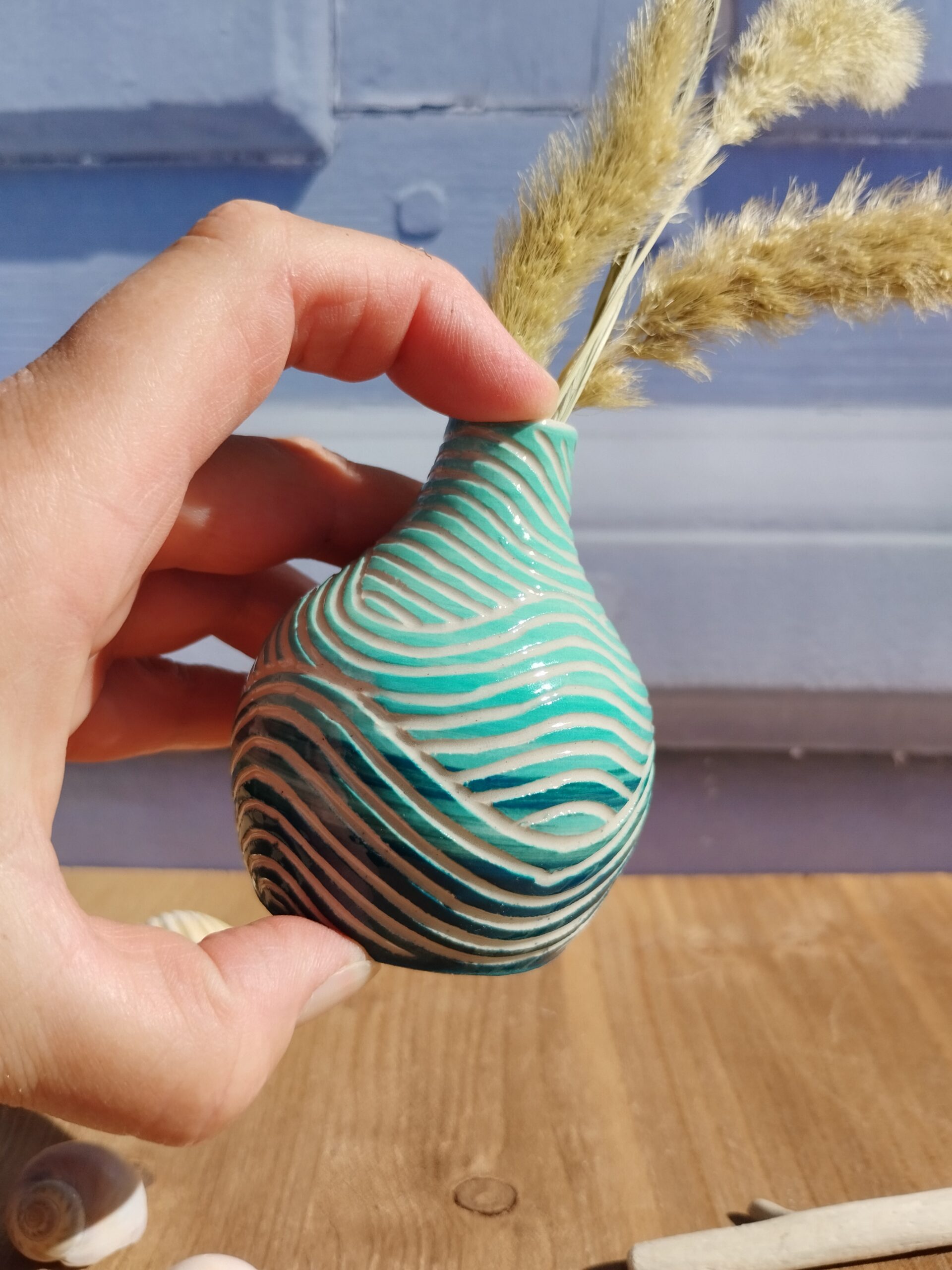 mini vase en céramique artisanale. Fond en dégradé de bleus. Motif de lignes gravées en forme de vagues