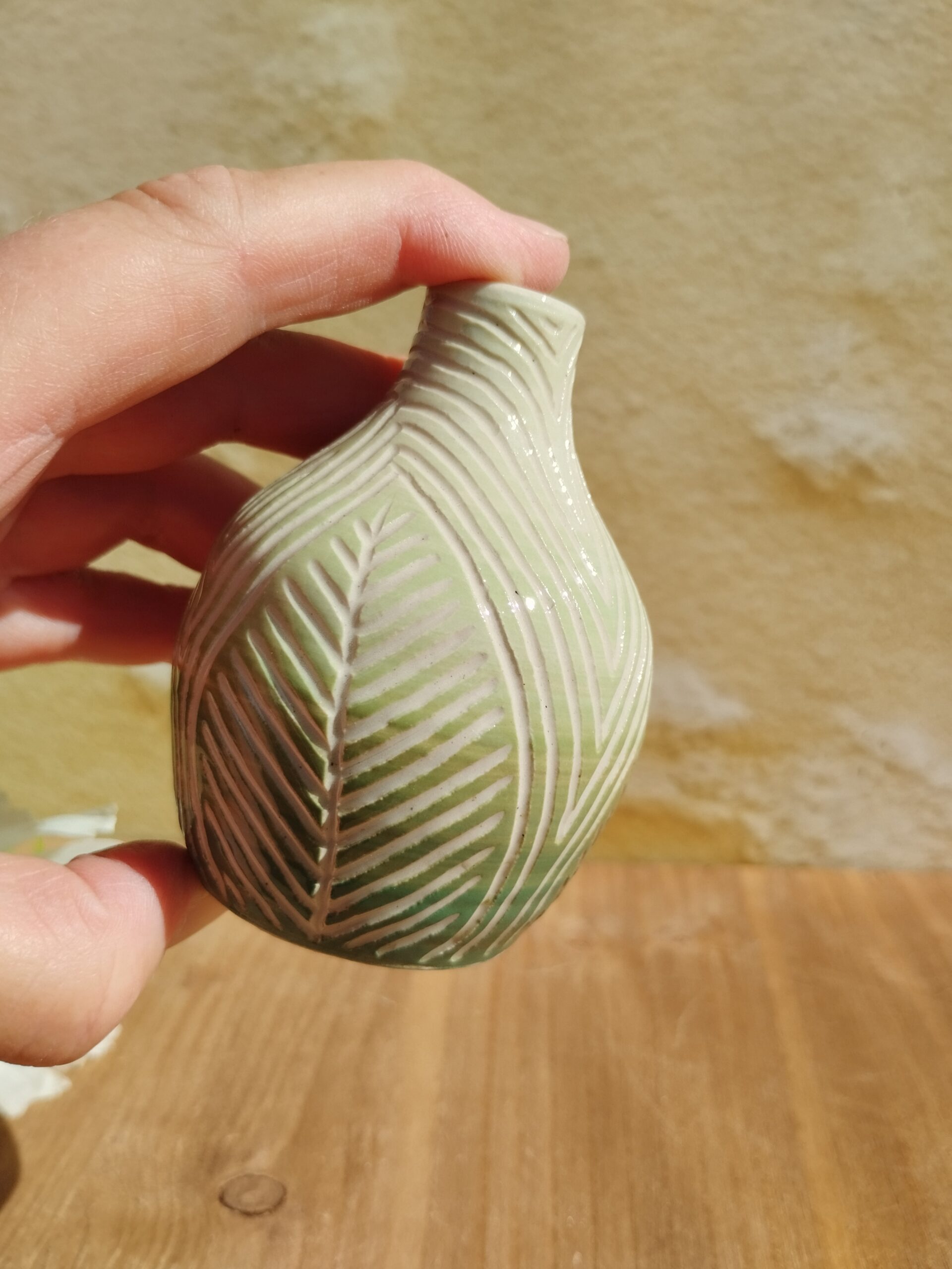 Mini vase en céramique artisanale. Fond en dégradé de vert. Motif de feuillage gravé