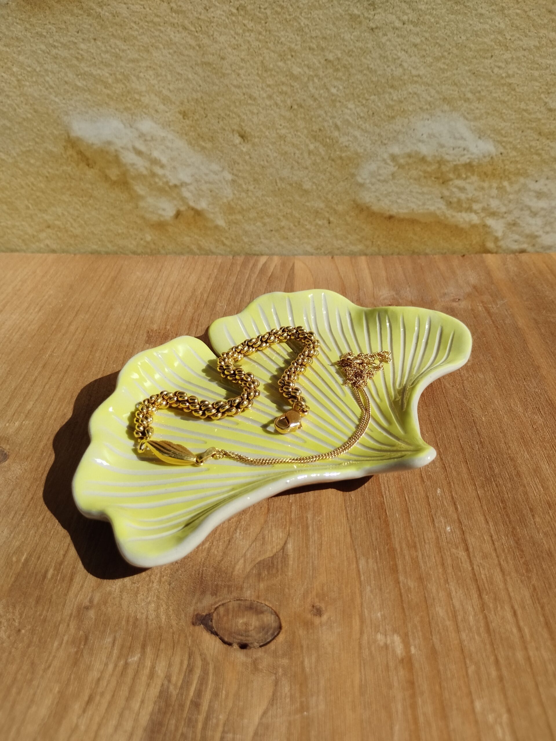 Coupelle à bijoux en céramique artisanale. Fond coloré en dégradé de jaune vif et vert clair. Motif de nervures gravées.