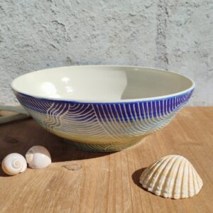 saladier en céramique artisanale. Fond en dégradé de bleu et vert. Motif de lignes gravées rappelant les mouvements de l'eau