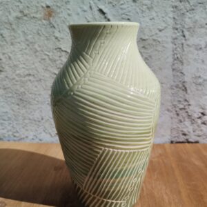 Vase en céramique artisanale. Fond coloré en dégradé de vert. Motif de lignes gravées