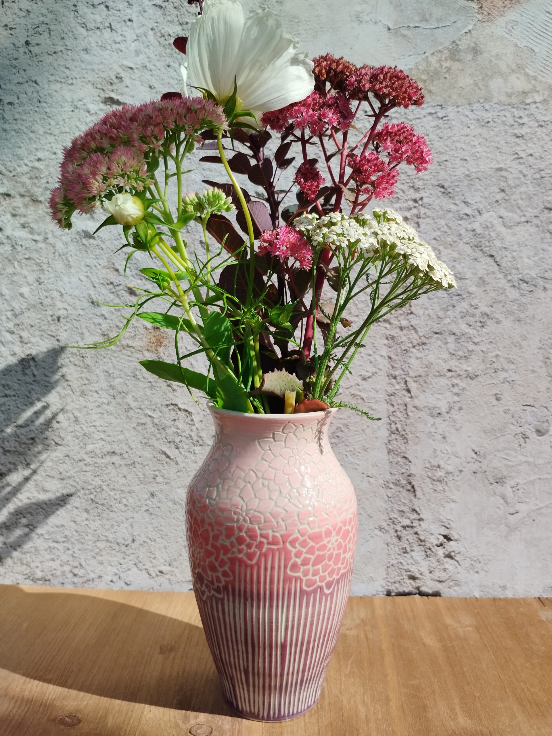 vase en céramique artisanale. Fond en dégradé de rose. Motif de lignes gravées