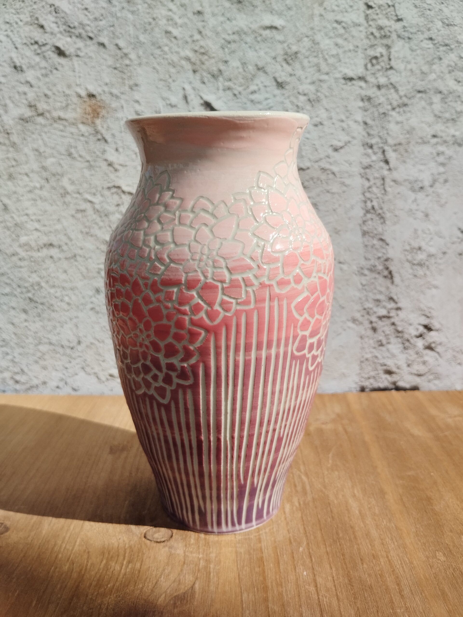 vase en céramique artisanale. Fond en dégradé de rose. Motif de lignes gravées