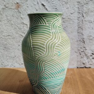 vase en céramique artisanale. Fond en dégradé de vert et bleu. Motif de lignes gravées