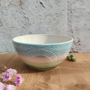 Saladier en céramique artisanale. Fond en dégradé bleu, rose, vert/ Motif gravé soleil levant sur la prairie