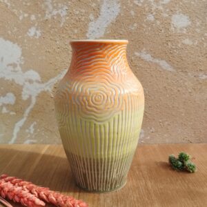 Vase en céramique artisanale. fond en dégradé de orange à vert. Motif de fleurs gravées